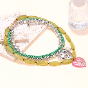 Detail of layered beaded necklace featuring a pink enamel heart and silver hollow pendant