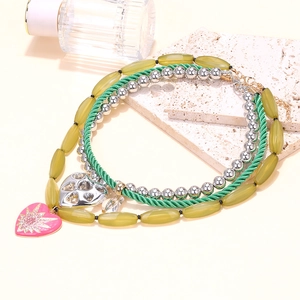 Layered beaded necklace with gradient heart charms on aesthetic stone and glass backdrop