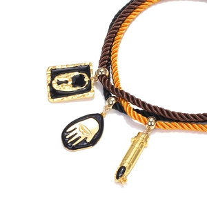 Detail of layered rope necklace with palm charm, lock, and enamel pendant accents
