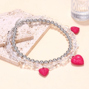 Detail of layered necklace with pink embossed heart pendants and mixed beads on a stone plate