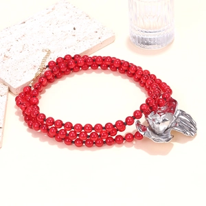 Detailed close-up of triple-strand red beaded necklace with large silver floral pendant