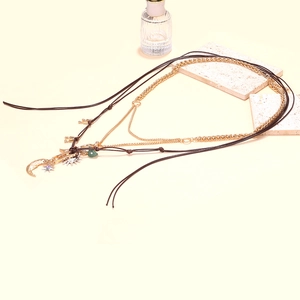 Close-up of bohemian layered necklace featuring moon, star and green heart pendants