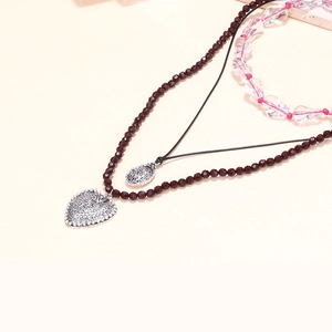 Detail of beaded necklaces with red faceted beads and intricate vintage heart pendant