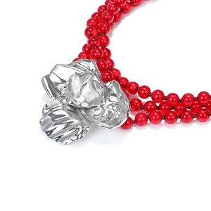 Close-up of triple-layered red beaded necklace with large metallic silver flower pendant