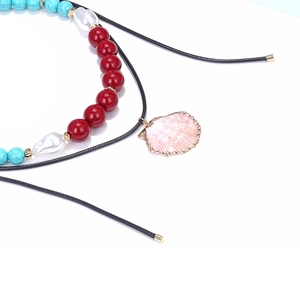 Detail of colorful beads, pearl accents, and pink shell pendant on a black cord necklace