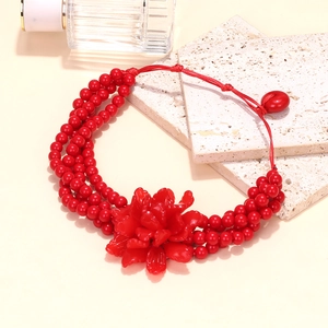 Close-up of a handmade red layered beaded necklace featuring a large 3D resin flower pendant