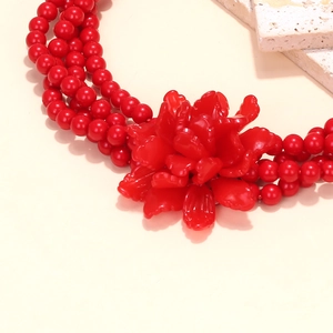 Close-up of a vibrant red triple-layered beaded necklace with a 3D resin floral pendant
