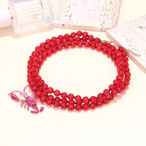 Three-layer red beaded necklace featuring a purple lobster pendant and golden clasp