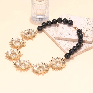 Détail du collier à perles avec tournesols dorés et perles en résine noire brillante
