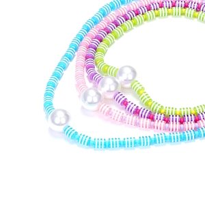 Gros plan de perles en résine rayées colorées et grandes perles blanches sur un collier