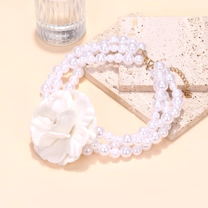 Close-up of double-layer pearl necklace with a detailed white camellia fabric flower charm