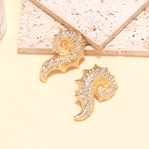 Detailed close-up of gold shell and seahorse earrings with sparkling white rhinestones