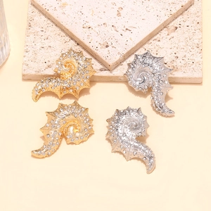 Detailed view of gold and silver conch stud earrings with sparkling rhinestones on stone