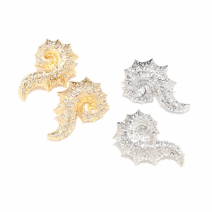 Macro detail of conch shell earrings in gold and silver with crystal rhinestones