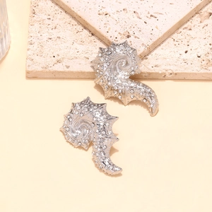 Detailed view of silver shell earrings with sparkling rhinestones on natural stone