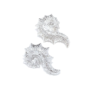 Detail of silver conch earrings featuring sparkling inlaid rhinestones on a white background