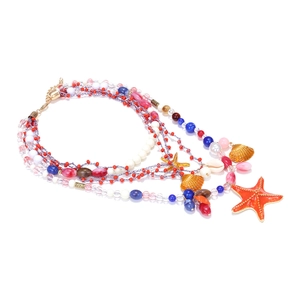 Multilayer beaded necklace with orange starfish and shell charms on white background