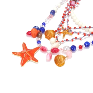 Macro view of multi-layer beaded necklace with orange starfish and seashell pendants