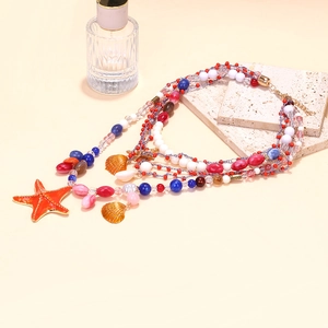 Detail of multi-layer beaded necklace featuring orange starfish and gold shell pendants