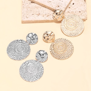Detailed view of large round drop earrings featuring metallic spiral relief and hammered texture