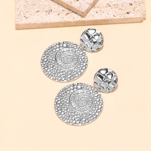 Silver spiral metal drop earrings with retro geometric design on beige background