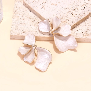 Dettaglio di orecchini a fiore in smalto bianco con bordi dorati e petali testurizzati
