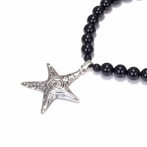 Beaded necklace with black glossy pearls and a silver starfish pendant on white background