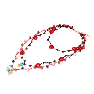 Collier multi-rangs perles fait main avec pendentifs cœur et poisson sur fond blanc