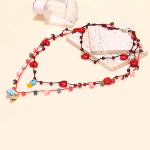 Vue détaillée du collier en perles tissées avec breloques cœur rouge et poisson bleu sur pierre