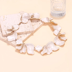 Close-up of handmade cream enamel flower petals with gold edges on an elegant necklace
