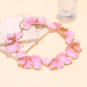 Close-up of pink enamel flower petals on a gold-plated link necklace with natural textures