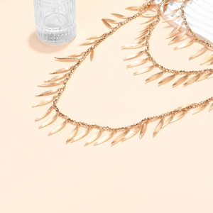 Macro detail of multi-layer gold beaded necklace with dense fringe leaf-shaped pendants