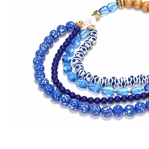 Dettaglio della collana boho multistrato con perline in resina blu e inserti in legno