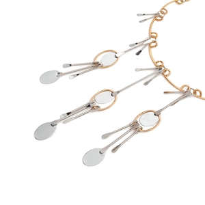 Détail d'un collier multicouche en or et argent avec des pendentifs franges en métal