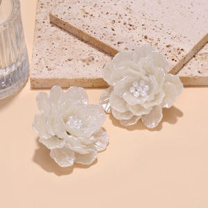 Détail de boucles d'oreilles fleurs faites main avec pétales en résine et perles nacrées