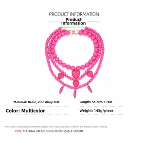 Détail d'un collier multicouche à perles rose vif avec pendentifs cœur et piment