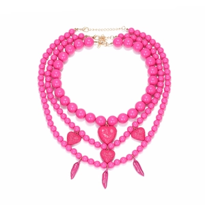 Collier bohème multicouche rose vif avec pendentifs cœur et piment sur fond blanc éclatant