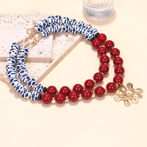 Close-up of double-layered beaded necklace with red and blue beads and evil eye palm pendant