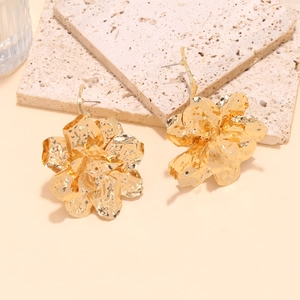 Detailed view of large gold metallic flower earrings with textured hammered petals
