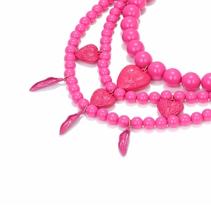 Détail d'un collier de perles rose multicouche avec pendentifs en cœur et structure