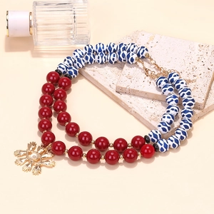 Layered beaded necklace featuring red and blue beads with a gold evil eye hand pendant