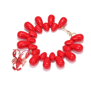 Detail of red water-drop beads and lobster pendant on a gold-plated beaded necklace