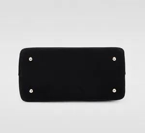 Detail view of black leather handbag base with four golden protective metal feet
