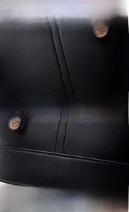 Close-up of black lychee texture leather with precision stitching and metal feet details