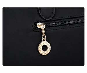 Close-up of golden ring zipper puller on black quilted fabric handbag