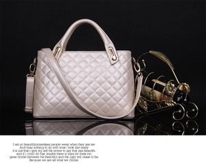 Close-up of champagne quilted leather handbag with gold hardware on reflective surface