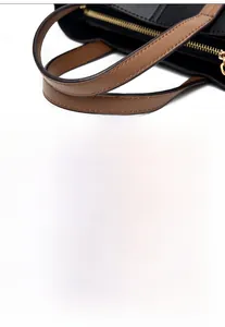 Detail of color-block leather handbag featuring gold zippers and protective bottom rivets