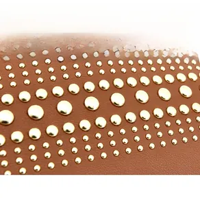 Dettaglio borsa a tracolla in pelle marrone con borchie metalliche dorate e grana