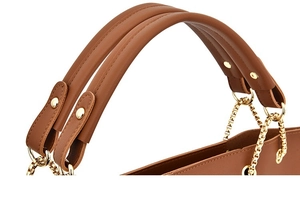 Dettaglio dei manici borsa marrone caramello con catene dorate e finiture rivetti
