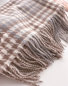 Close-up of woven houndstooth check scarf texture with soft fringe tassel details